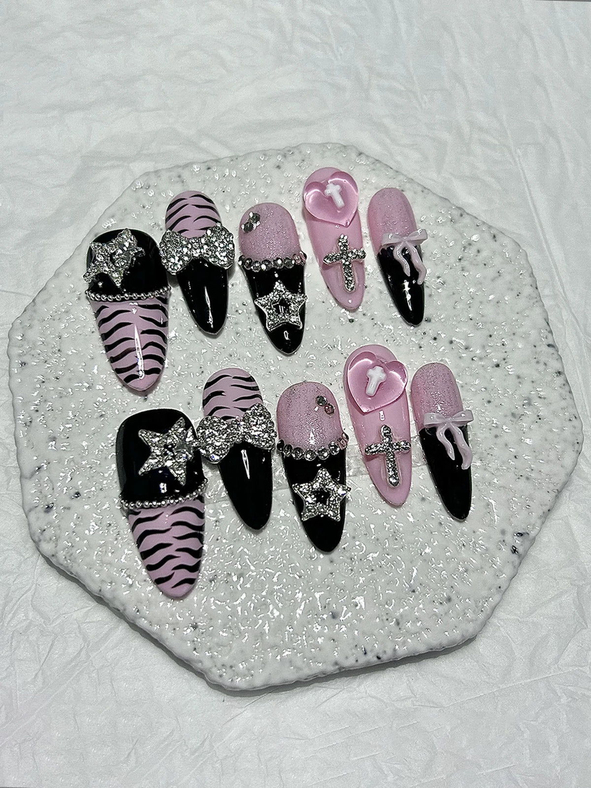 A set of glitter diamond press on nails featuring black, pink, and zebra print designs displayed on a white surface.