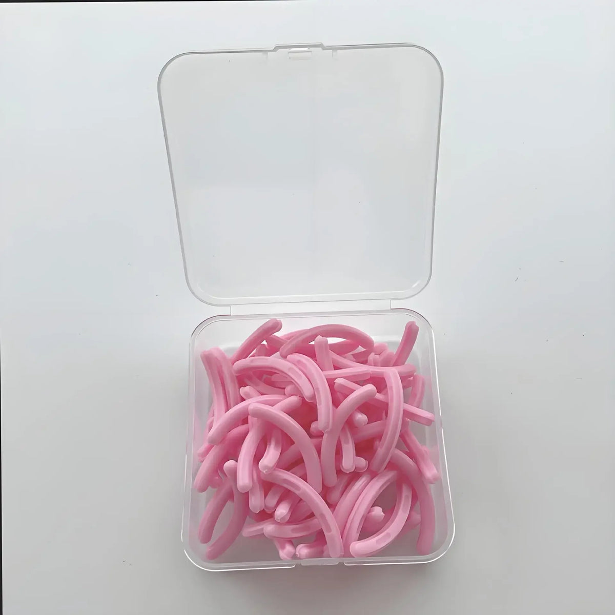 A clear plastic container holds 30 pink reusable silicone eyelash curler pads.