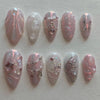 A collection of 24 pink heart pearl press-on fake nails featuring iridescent and glitter finishes.