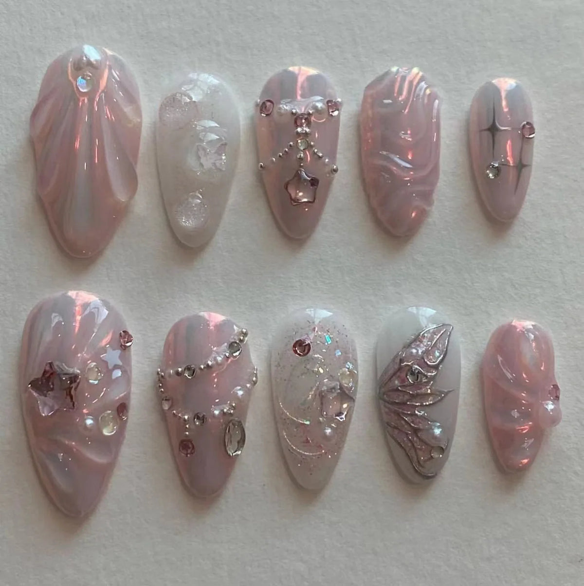 A collection of 24 pink heart pearl press-on fake nails featuring iridescent and glitter finishes.