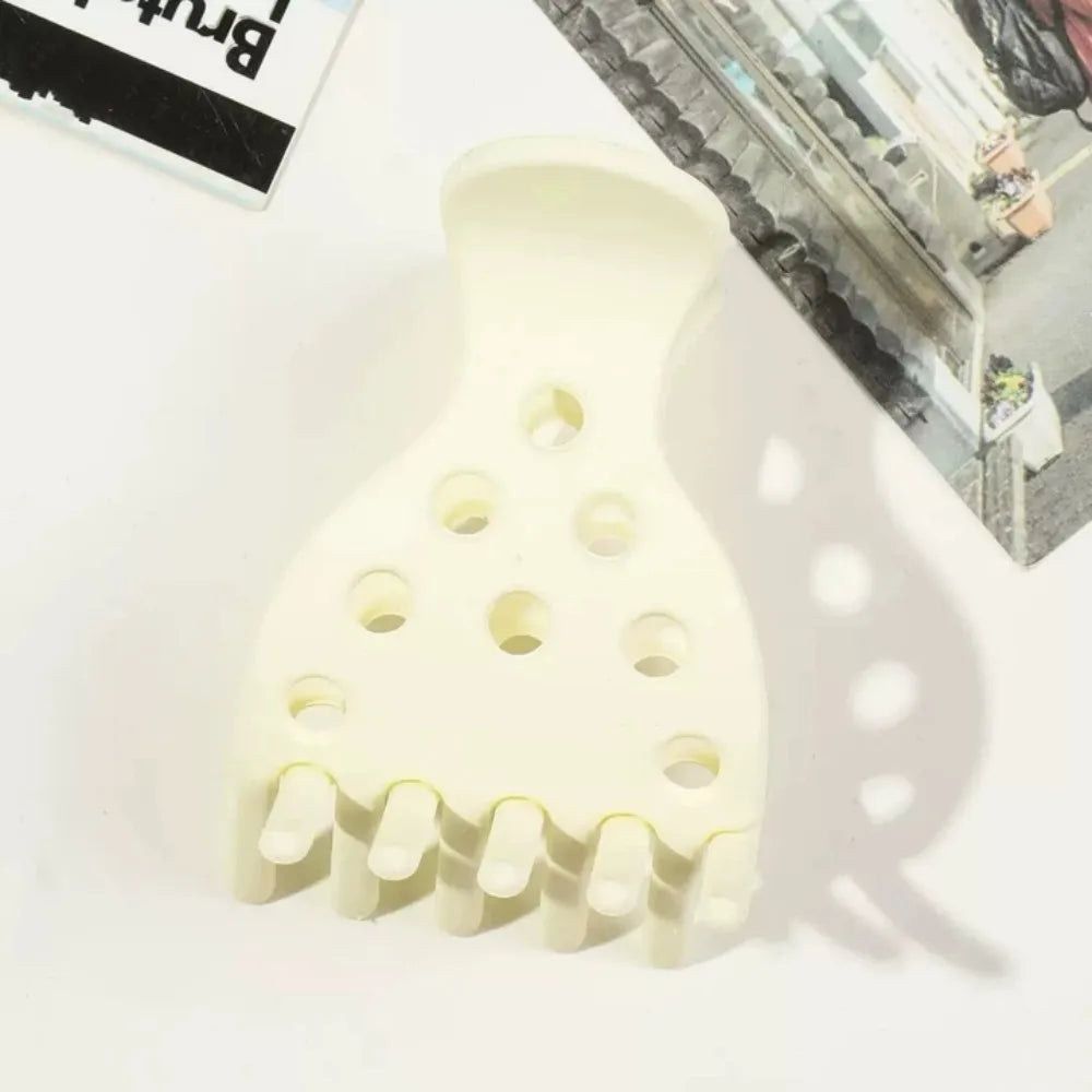 A white plastic root lifting hair clip with multiple prongs shown against a light background.