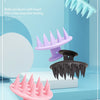 Un set de quatre brosses à dents en gel de silice pour shampoing, en différentes nuances de rose et noir, exposées sur un fon