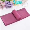 A pink mesh sport towel rolled up on a white surface next to purple and yellow flowers.