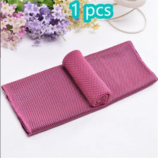 Serviette de sport rose en maille roulée sur une surface blanche à côté de fleurs violettes et jaunes.