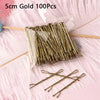 A bundle of 100 gold metal U-shaped hair pins laid out on pink fluffy material.