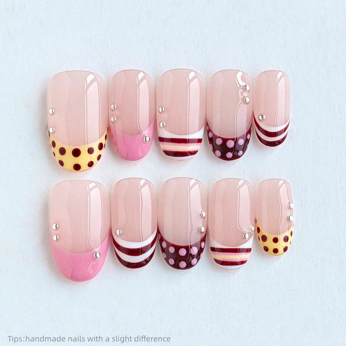 A set of ten pink press-on nails featuring a polka dot pattern and silver bead accents.