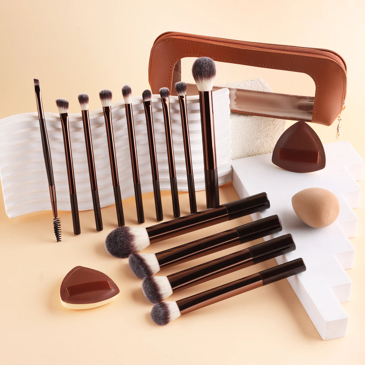 A set of thirteen professional makeup brushes in brown and black with a leather storage case and white background.
