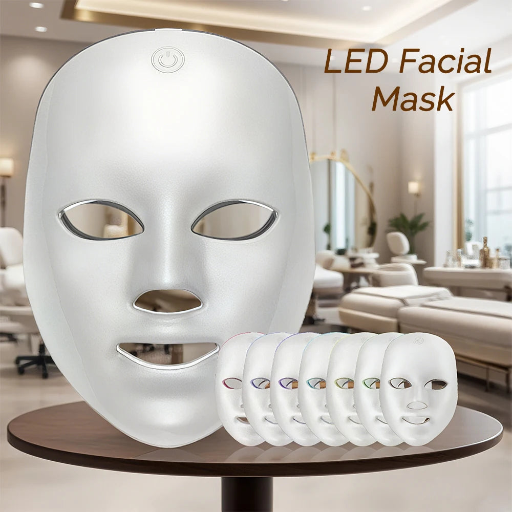 Una mascarilla facial LED blanca con siete lentes de colores exhibida en un soporte.