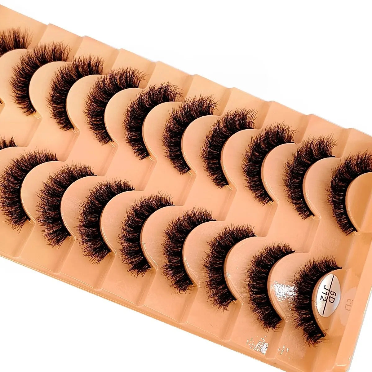 Un plateau de faux cils de renard fabriqués à la main, de couleur pêche ou nude, disposés en rangées.
