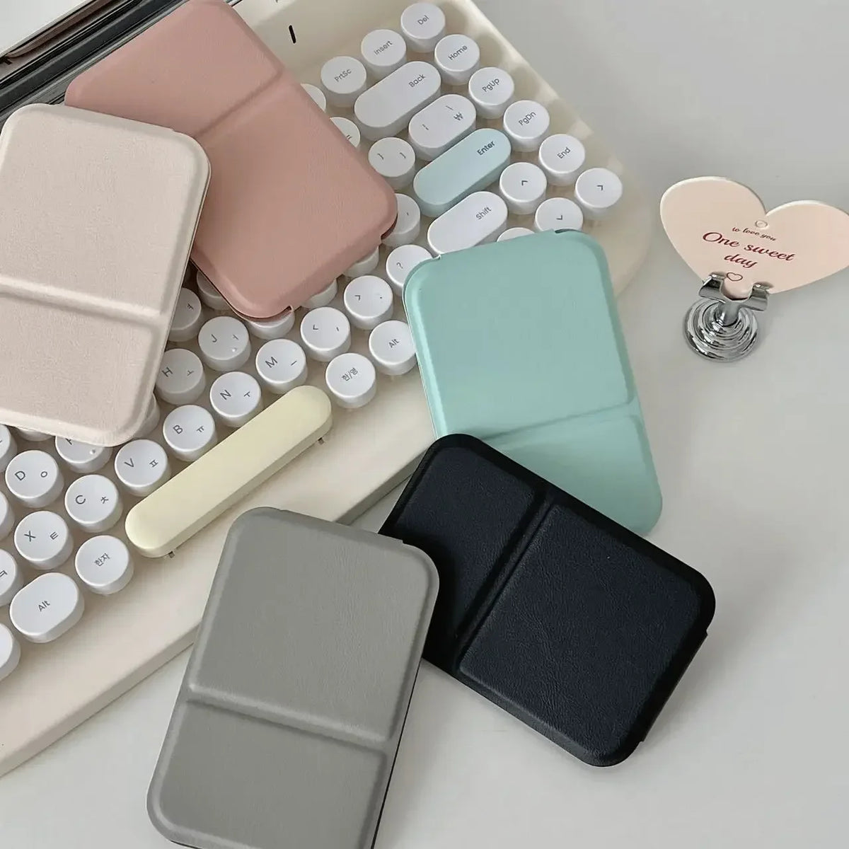 A collection of portable makeup mirrors in various pastel and neutral colors arranged on a white background.