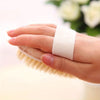 Una mano sostiene un cepillo exfoliante de cuerpo con cerdas naturales blancas.