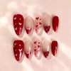 A set of ten glossy red and white almond shaped press-on nails with heart designs.