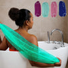 A woman is using a bright green African net exfoliating bath sponge in a white bathtub.