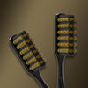 A black toothbrush with yellow and black bristles is shown against a brown background.
