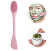 A pink double head silicone face cleansing brush next to a green facial mask and a small spoon.