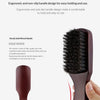 A close-up of a dark brown wooden boar bristle hair and beard brush being held by a hand.