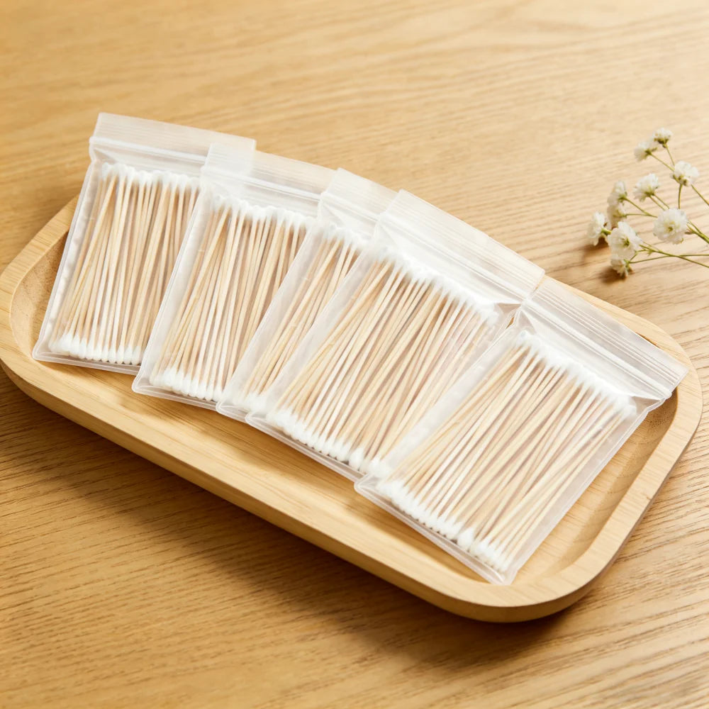 A set of precision wooden cotton swabs packaged in clear plastic on a wooden tray.