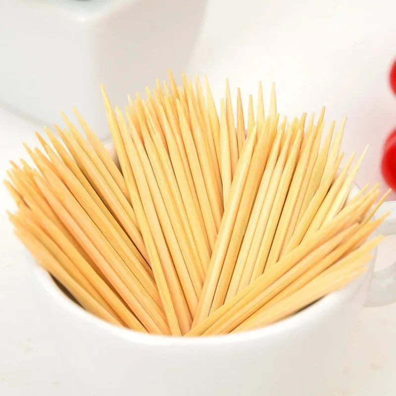 Una pila de mondadientes de bambú natural en una taza blanca.