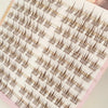 A close-up of natural look brown eyelash clusters displayed on a sheet.