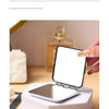 Miroir portable mini à pliage ouvert sur un support blanc.