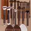 A collection of 14 professional makeup brushes and sponges in various shades of brown and black.