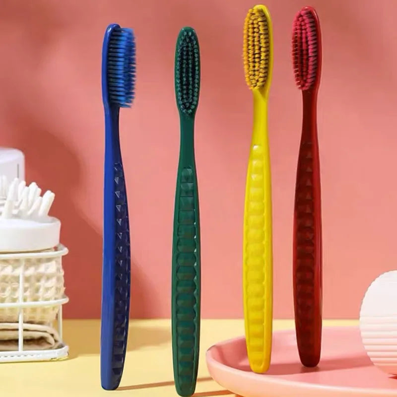 Un set de trois brosses à dents colorées et douces, bleues, vertes et rouges, présentées sur un plateau rose.