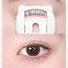 Un recourbe-cils à griffes de chat blanc est positionné sur un œil, montrant son utilisation pour recourber les cils.