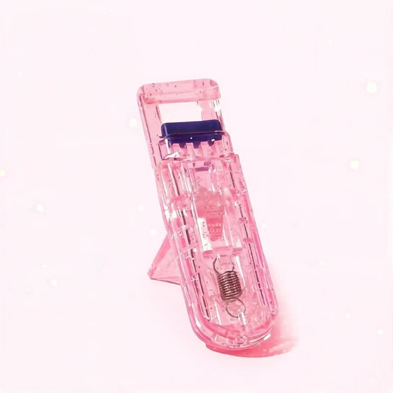 A pink portable mini eyelash curler set with a metal coil visible.