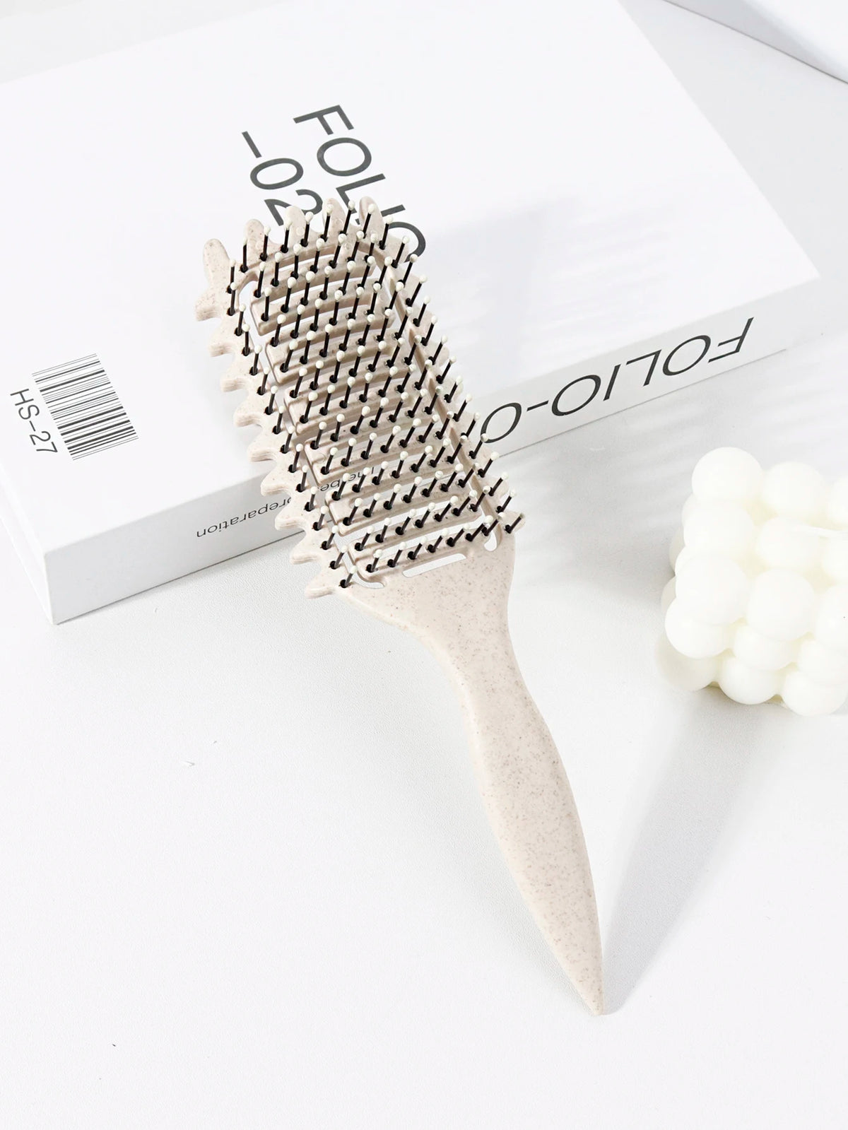 Peigne pour cheveux bouclés beige clair professionnel avec tête en plastique, à côté de sa boîte.