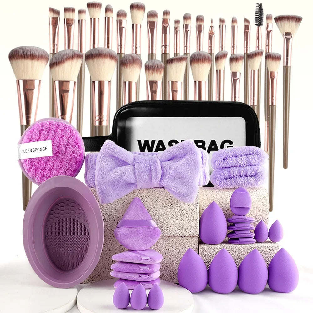 A collection of makeup brushes, sponges, and tools in various shades of purple and natural tones.