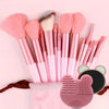 A collection of pink and nude makeup brushes, including various sizes and shapes, displayed on a pink background.