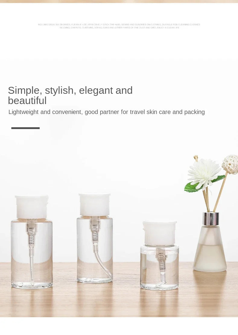 Three clear glass refillable push-down pump dispenser bottles with white pump tops displayed on a wooden surface.