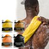 A person is using a yellow exfoliating sponge on their back in a shower, with other sponges visible.