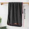 A dark gray microfiber cleaning towel hanging on a wooden rod against a white wall.