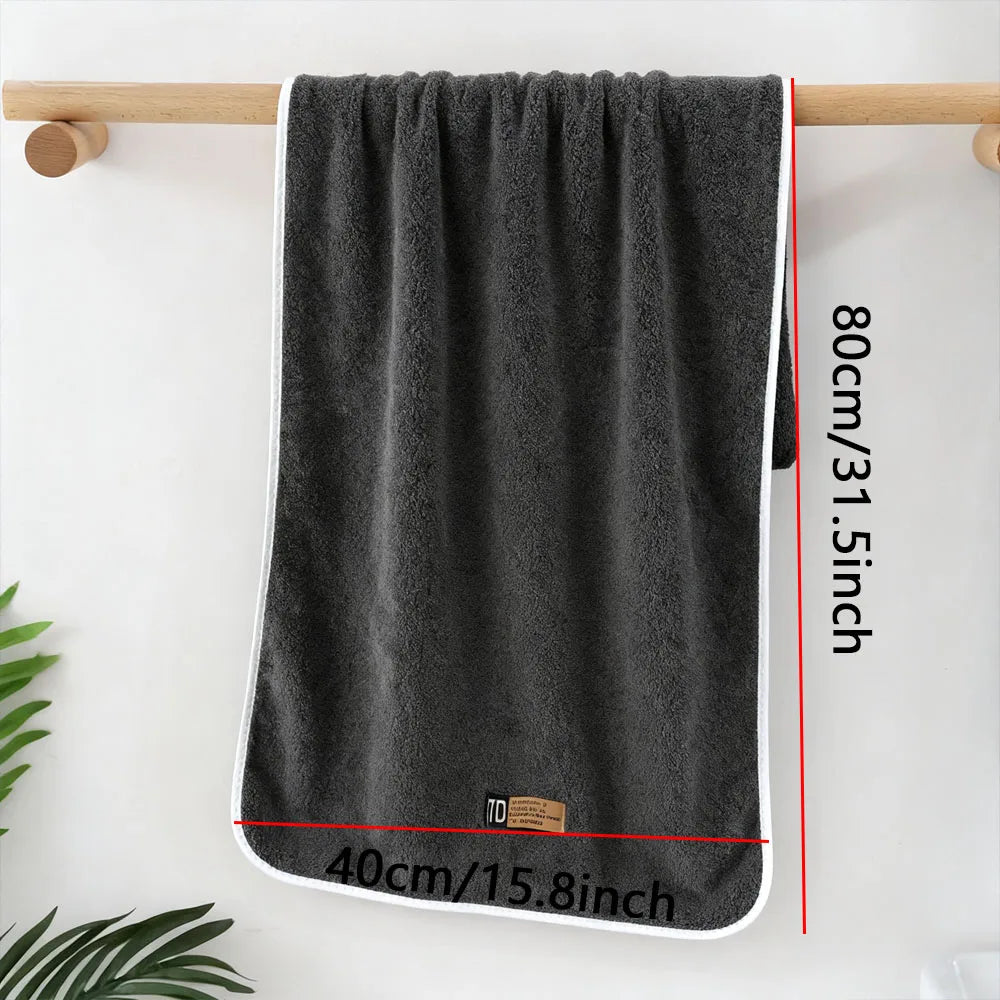 A dark gray microfiber cleaning towel hanging on a wooden rod against a white wall.