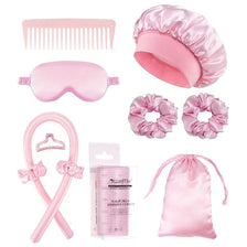 A set of pink hair styling tools including a comb, goggles, hair rollers, and a silk hair bag.