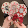 A hand holds a decorative makeup mirror set featuring pink and red accents with glittery frames.