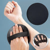 A hand is shown holding a black silicone shower brush and a circular black cleaning pad against a gray background.