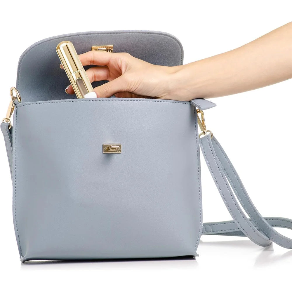 Une main tient une bouteille de parfum en cuir bleu clair dans une petite pochette en cuir gris.