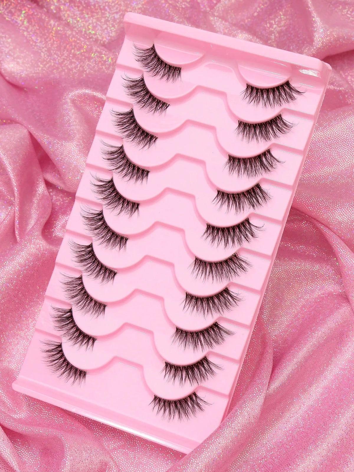 Pinke Kunststoff-Lash-Trage mit mehreren Reihen schwarzer Mink-Falschwimpern auf rosa Satin
