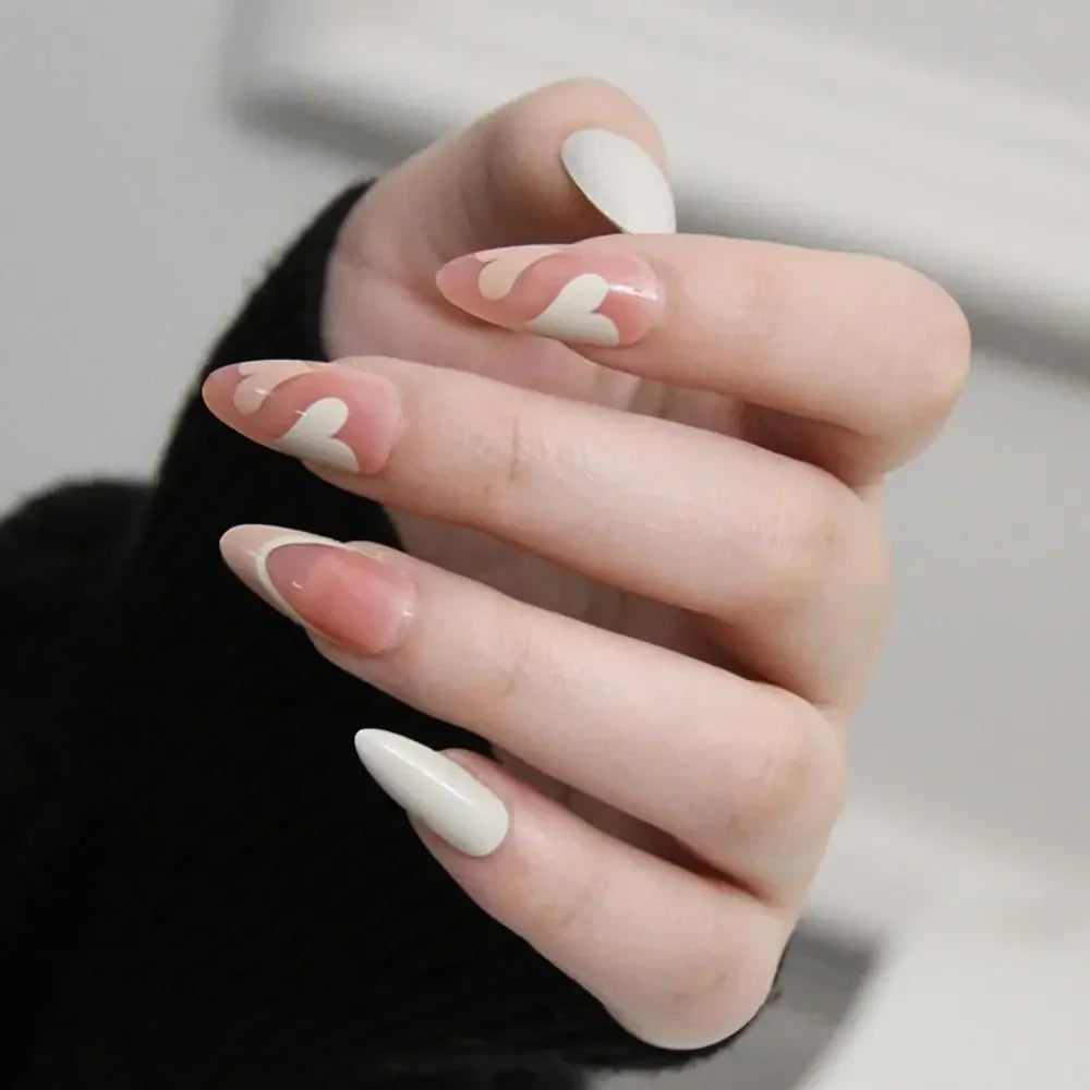 A hand displaying press-on false nails with a French wavy design featuring pale pink and white accents.