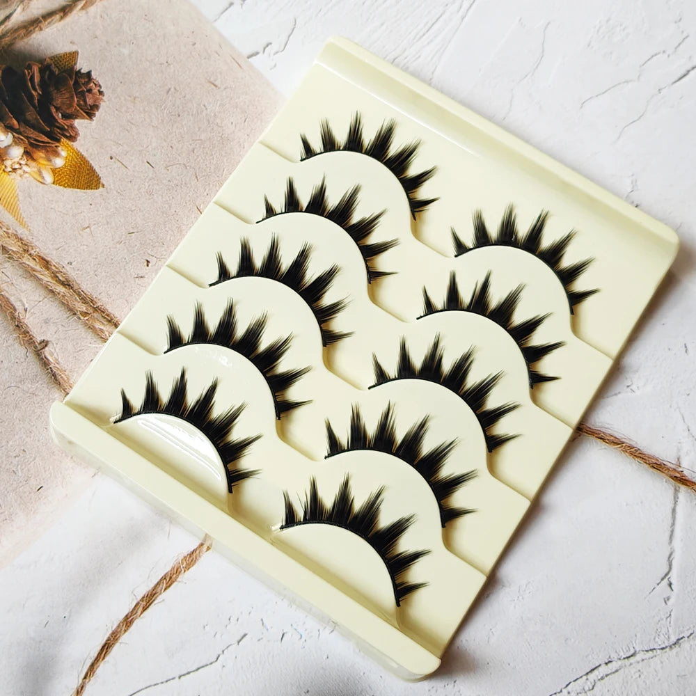 A square plastic tray holds five pairs of long and thick black false eyelashes for eye makeup.