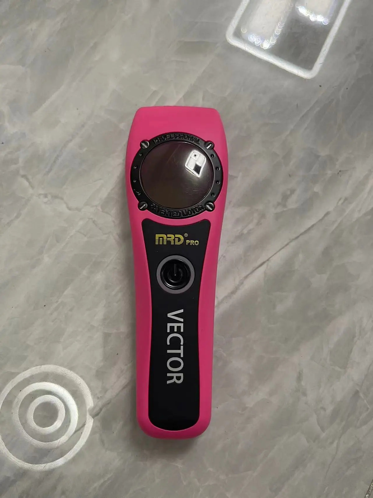 A pink electric hair trimmer labeled Vector MRD Pro resting on a light surface.