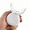 A hand holds a white teeth whitening kit with an U-shaped clear plastic tray.