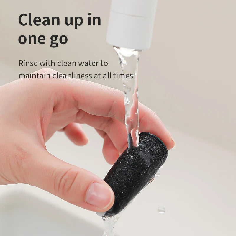 Une main rince un outil noir texturé sous un jet d'eau pour le nettoyer.