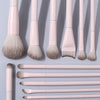 A set of thirteen professional makeup brushes in a pale pink color displayed vertically and horizontally.