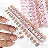 A hand holds a set of luxury nude pink ballet length false fingernails arranged on a pink plastic guide.
