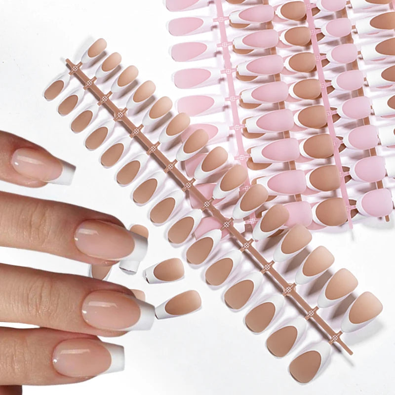 A hand holds a set of luxury nude pink ballet length false fingernails arranged on a pink plastic guide.