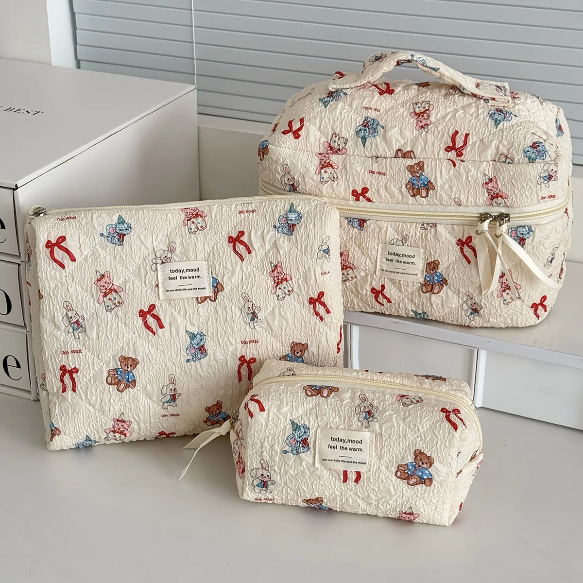 A set of quilted cotton makeup bags featuring a floral pattern and small teddy bear designs, displayed on a white surface.