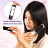 A woman is using a folding mini hair comb with a mirror to style her hair.